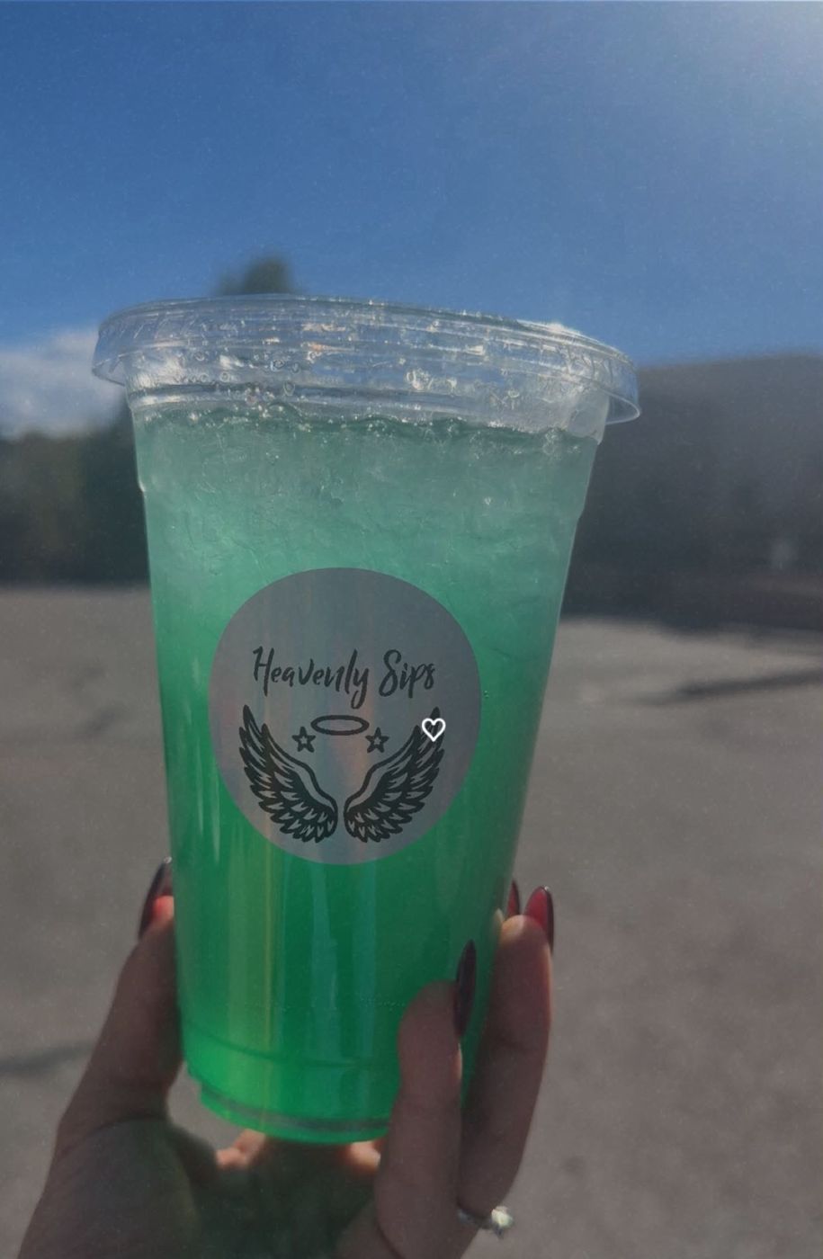 A bright green dirty soda held up against a blue Santa Fe sky